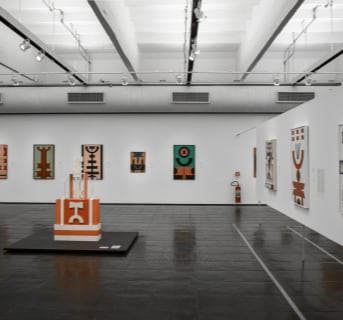 A view of the exhibition space with various abstract artworks on the wall.